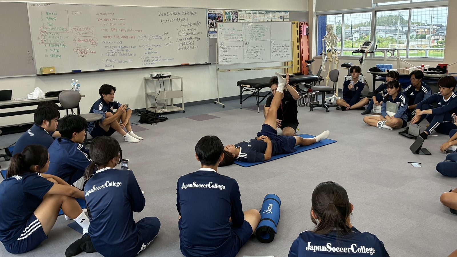 Dr.トレーニングの講師によるデモンストレーションを円になって見学するトレーナー志望の学生